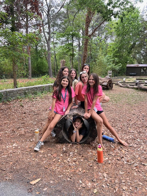 students smiling as they pose with a student inside the  hallowed out stump
