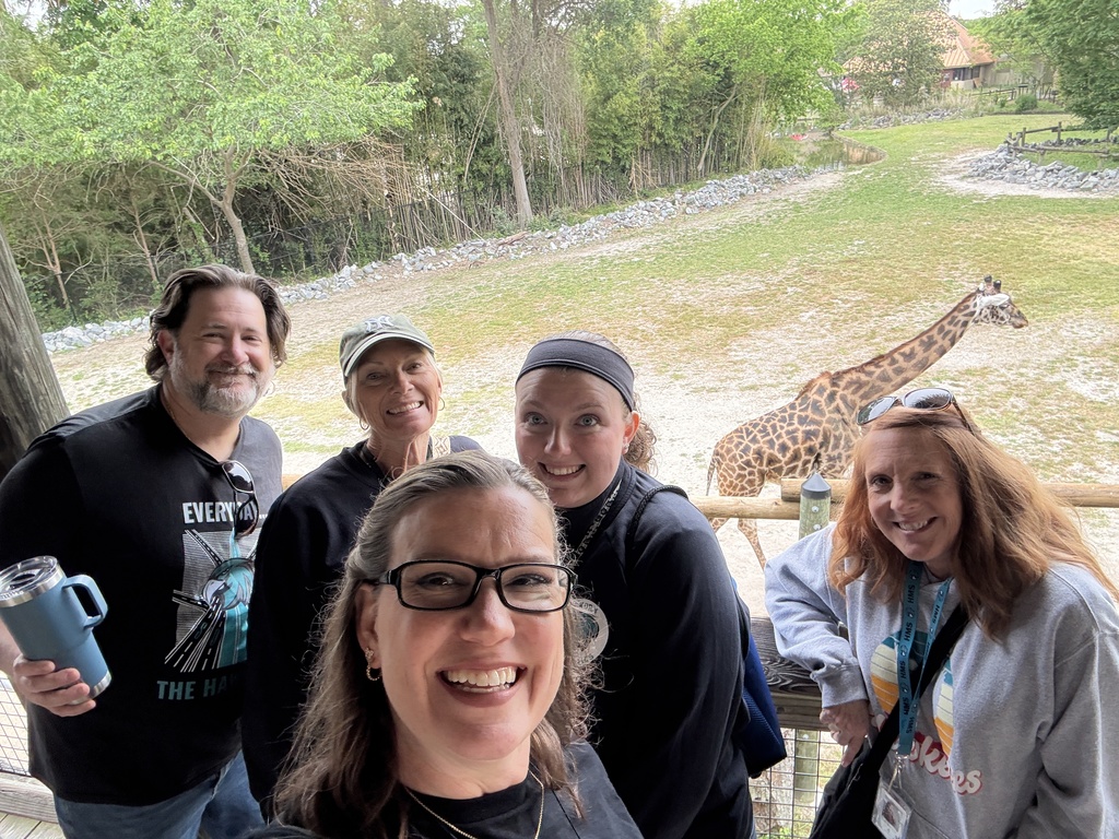 Teachers smiling with a giraffe in the background
