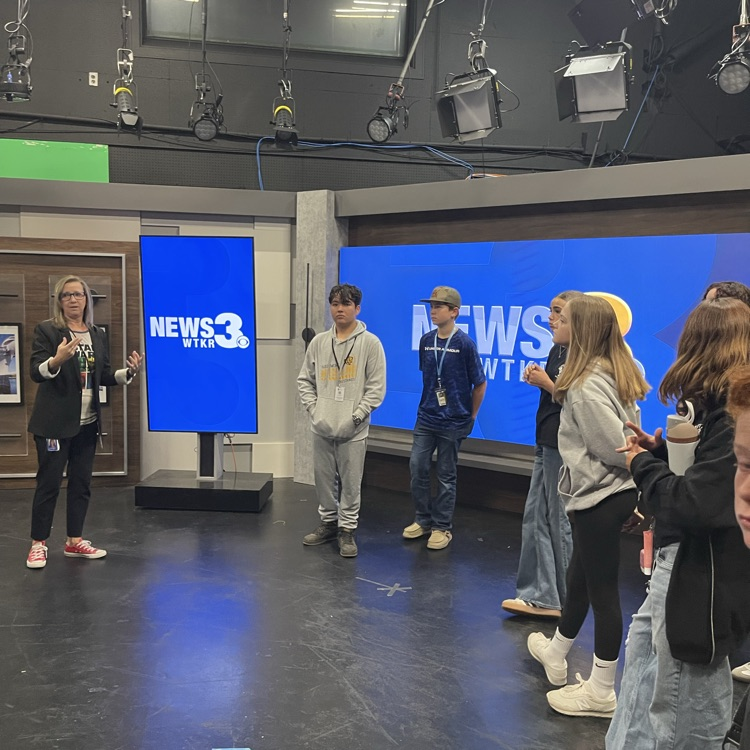 students stand around newsroom