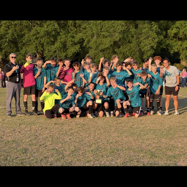 boys soccer team, coach, and principal posing with the trophy with the number 3 to represent their three peat performance