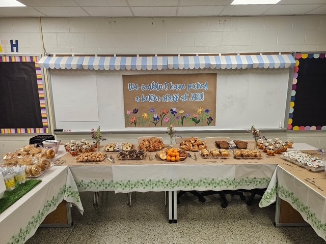 Display of all of the breakfast treats with a sign that says, "We couldn't have picked a better staff at SRI!" with pictures of flowers.