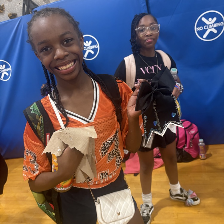 Student smiling and holding a bow they are going to decorate. 