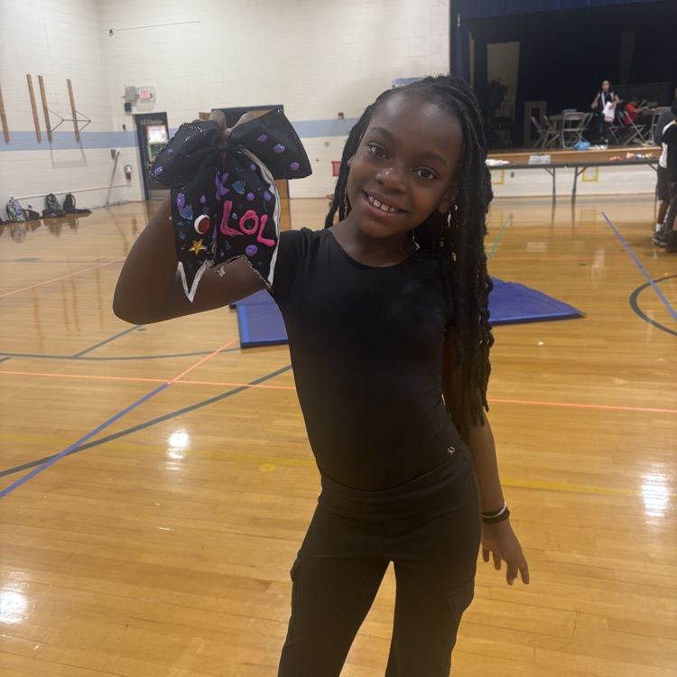 Student holding up decorate bow proudly. 