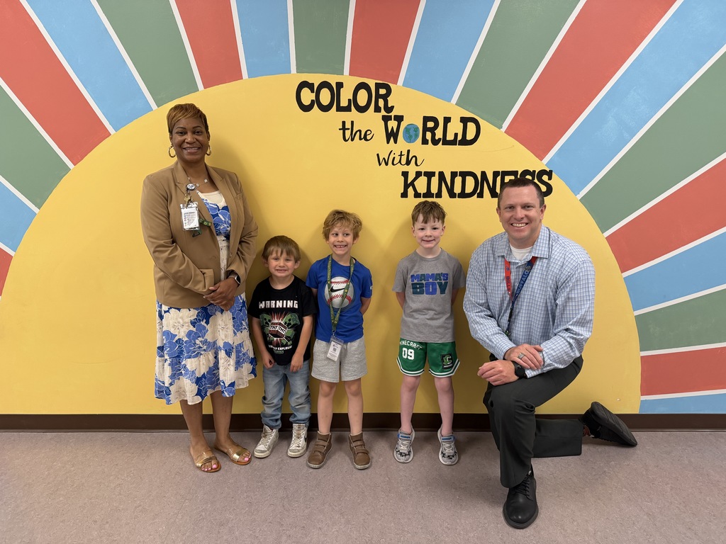 April Students of the Month from kindergarten, selected for demonstrating cooperation, standing together with school administrators while smiling for a group photo.