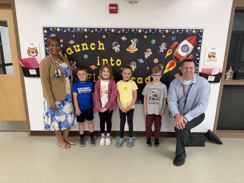 April Students of the Month from first grade, selected for demonstrating cooperation, standing together with school administrators while smiling for a group photo.