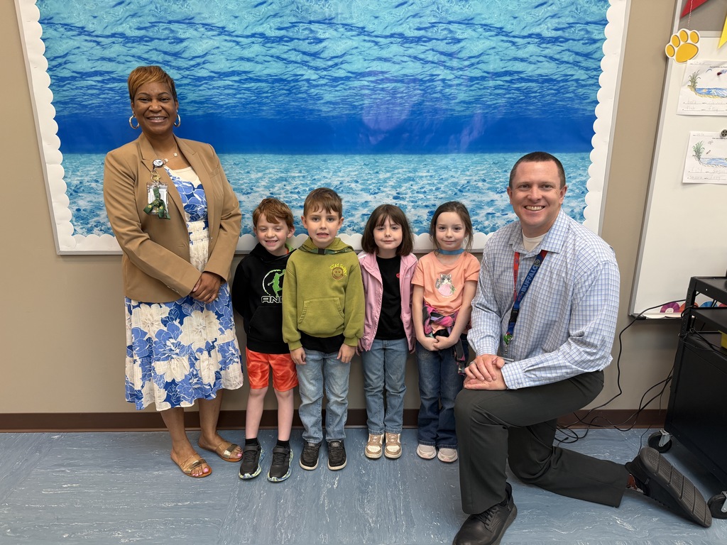 April Students of the Month from kindergarten, selected for demonstrating cooperation, standing together with school administrators while smiling for a group photo.