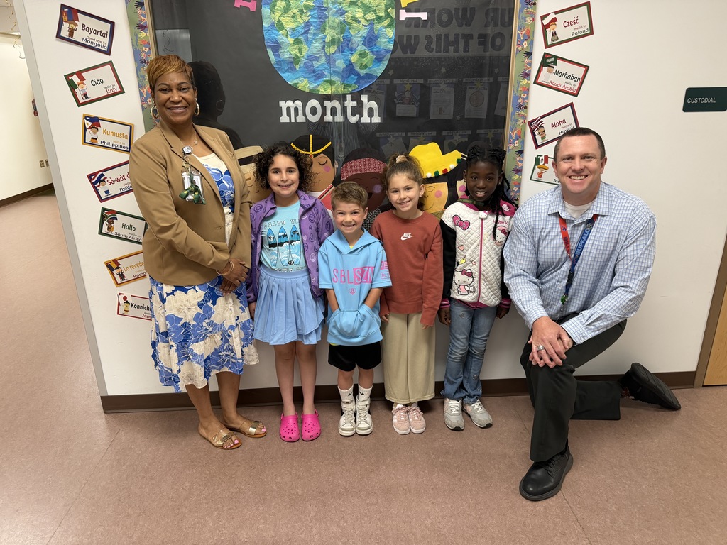 April Students of the Month from second grade, selected for demonstrating cooperation, standing together with school administrators while smiling for a group photo.