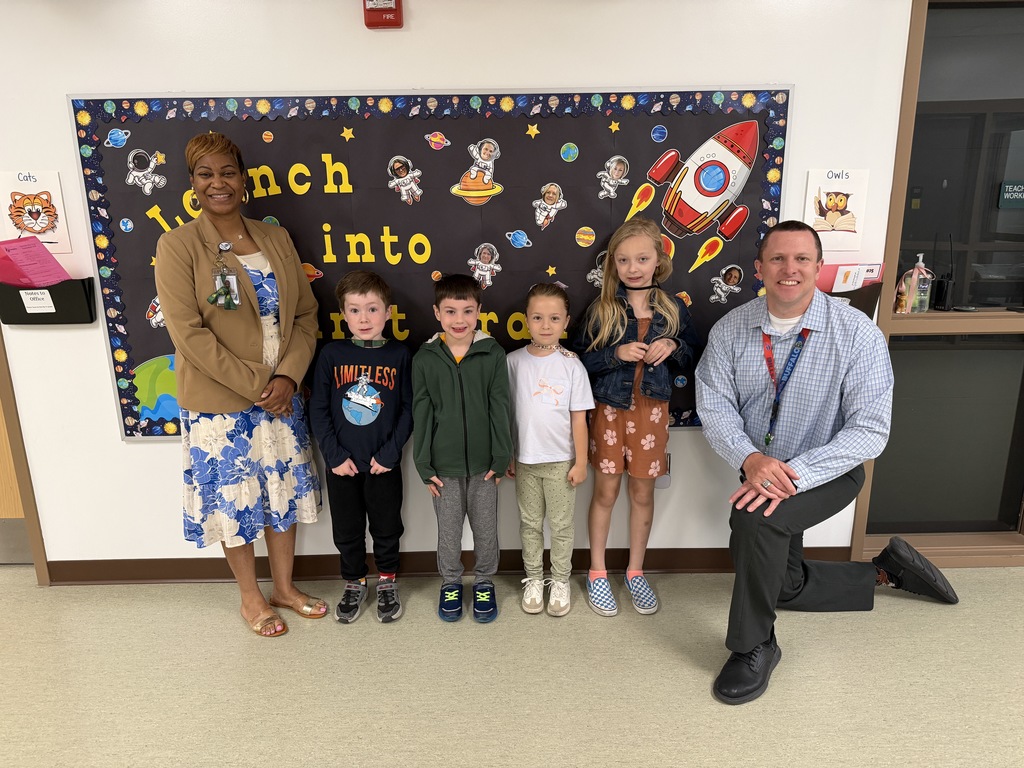 April Students of the Month from first grade, selected for demonstrating cooperation, standing together with school administrators while smiling for a group photo.