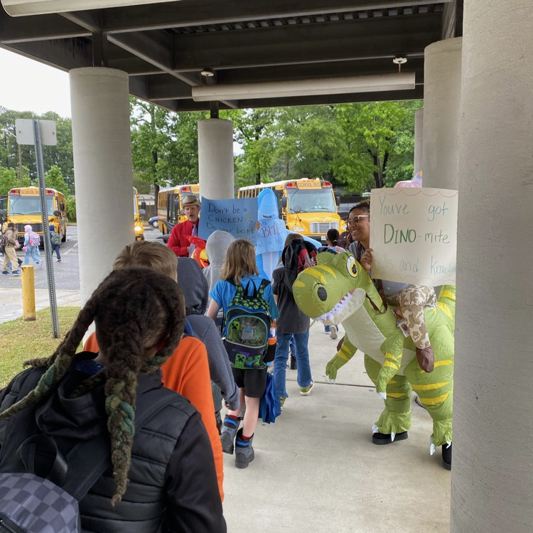 kids walking to buses with blow up costumes around them. 