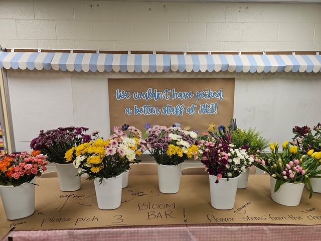 Sign that says We couldn't have picked a better staff at SRI! Table filled with buckets of flowers.