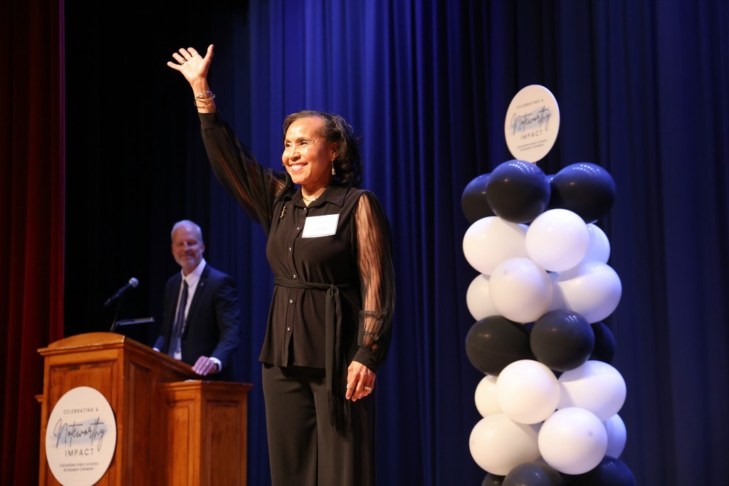 Retiree waving to the crowd on stage.