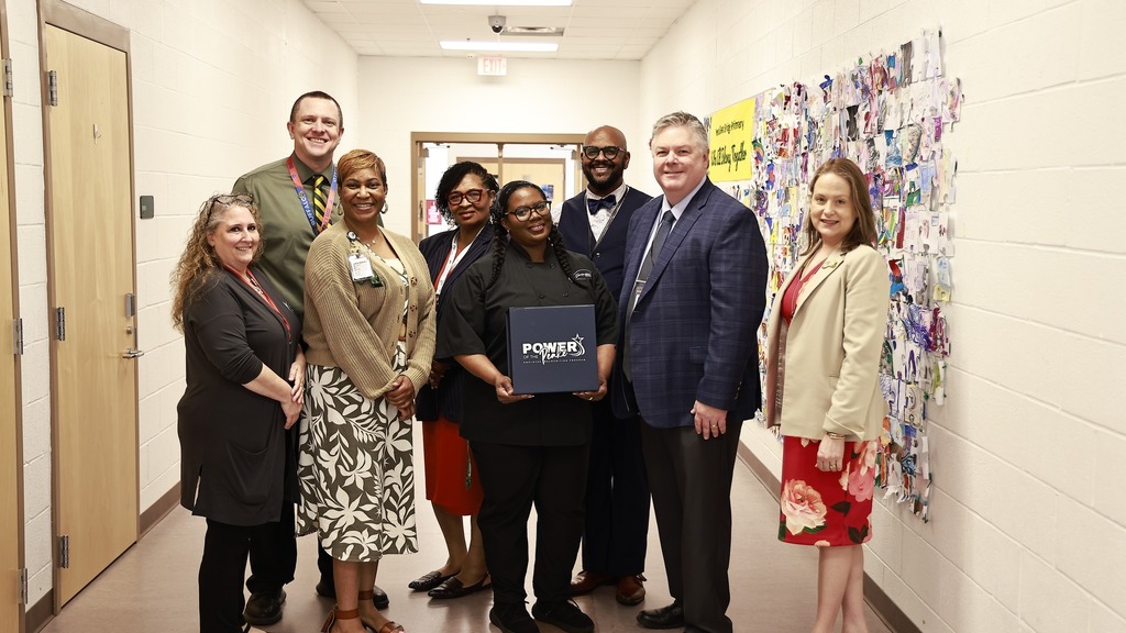 Group photo of Mrs. Moore, cafeteria manager, standing with school administrators and the superintendent while holding her “Power of the Peake” award certificate in recognition of her support and service to the school community.
