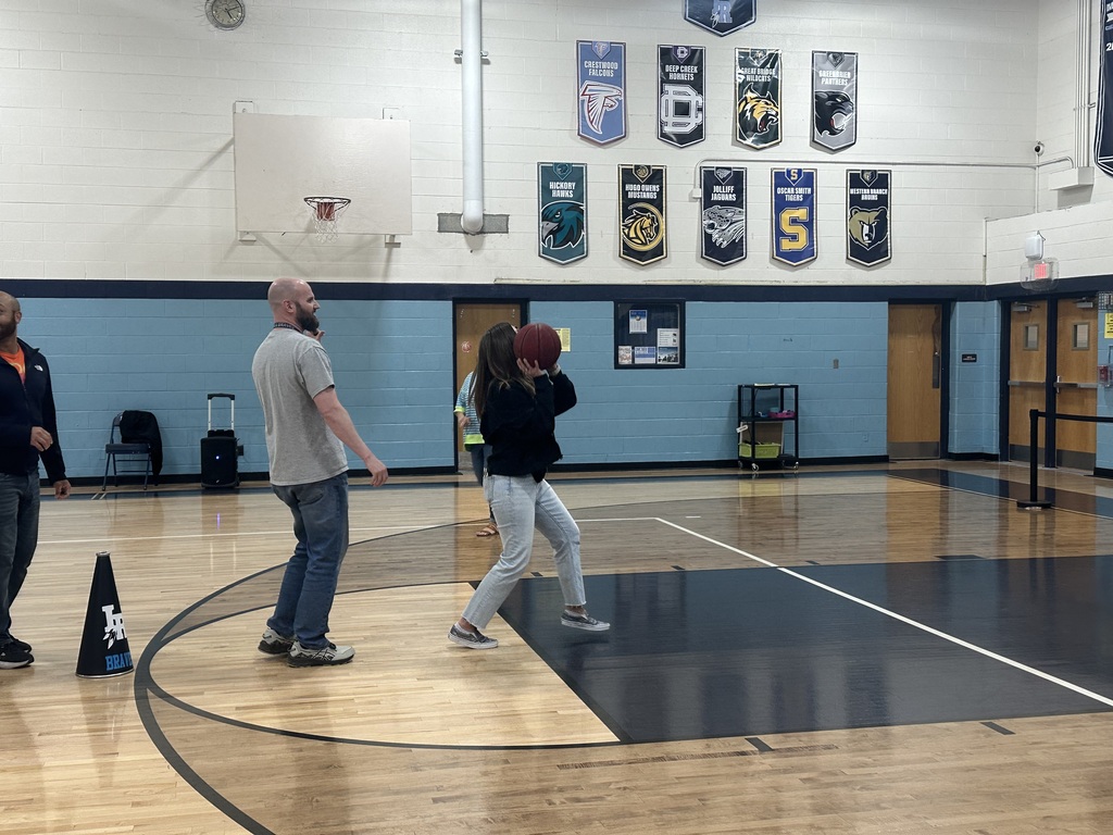 teachers shooting basketballs at the pep rally in a school gymnasium