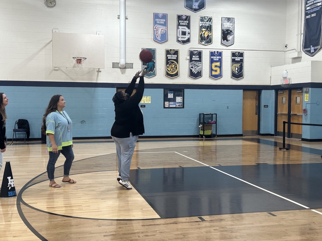 teachers shooting basketballs at the pep rally in a school gymnasium