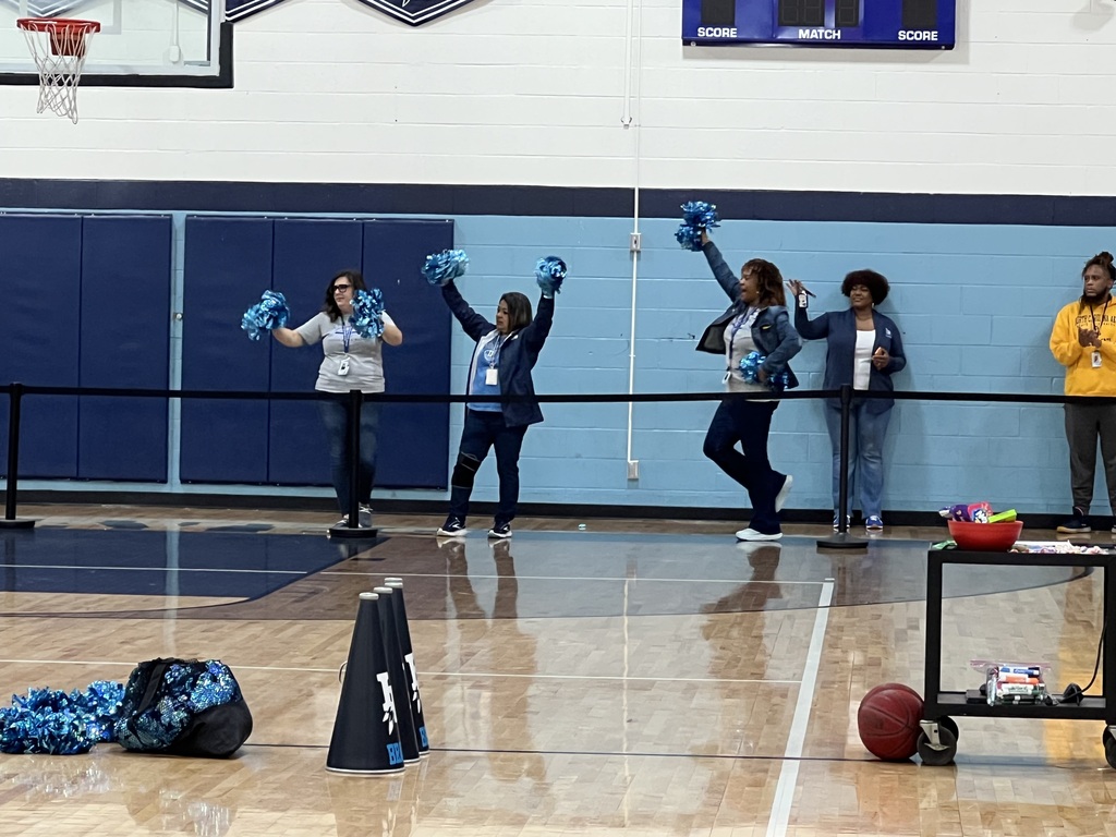 teachers cheering at a pep rally in a school gymnasium