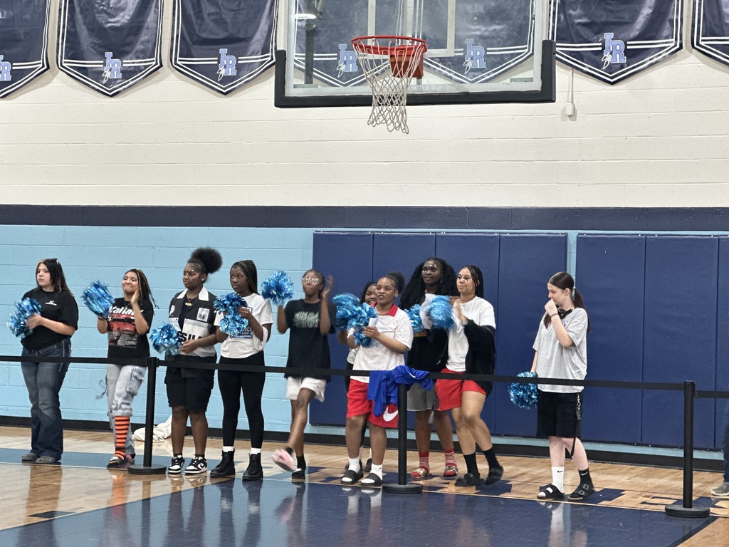 students cheering at a pep rally in a school gymnasium