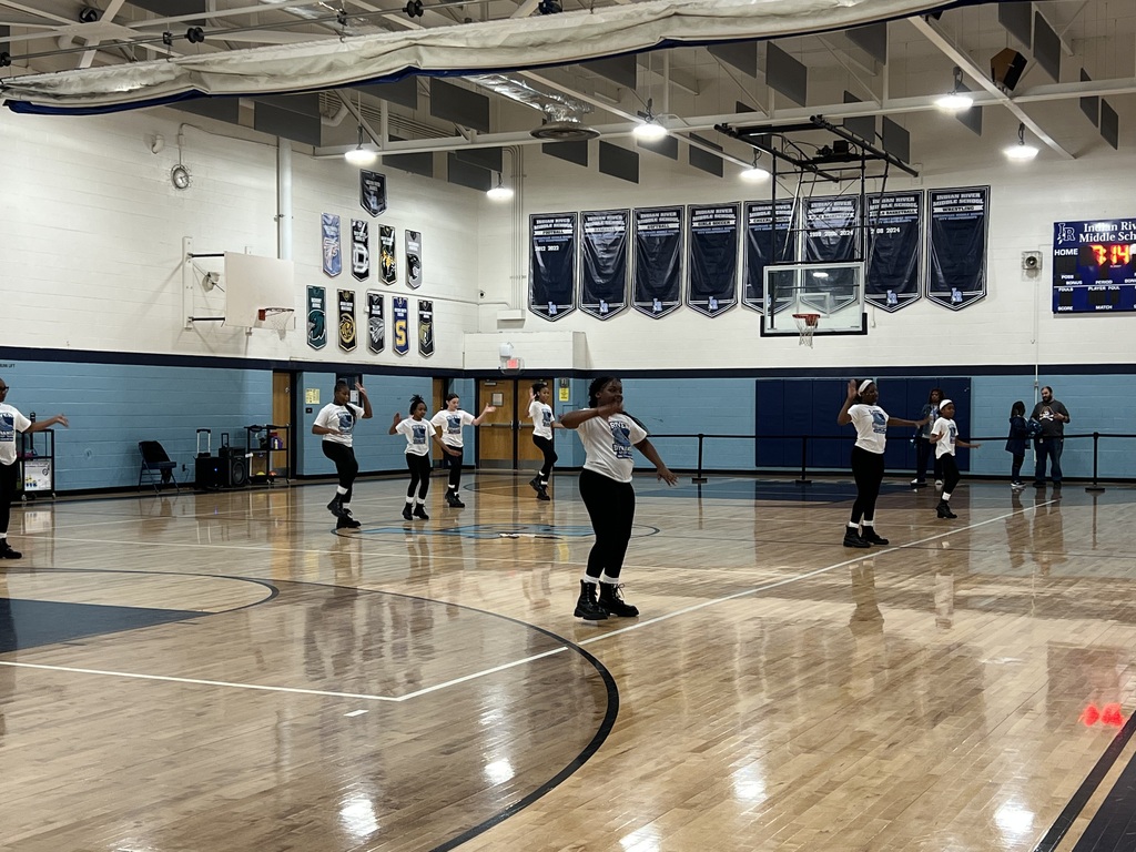 middle school step team performing in a gymnasium at a school pep rally