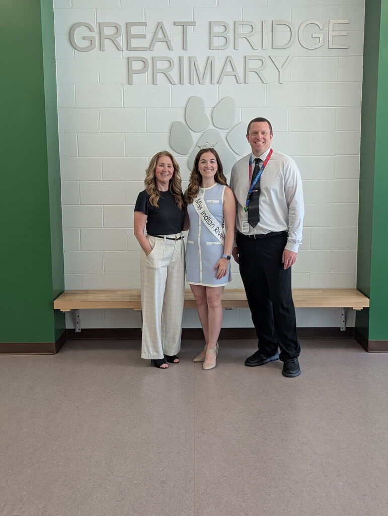 Miss Indian River poses smiling with the school principal and a professor during her visit to the school.