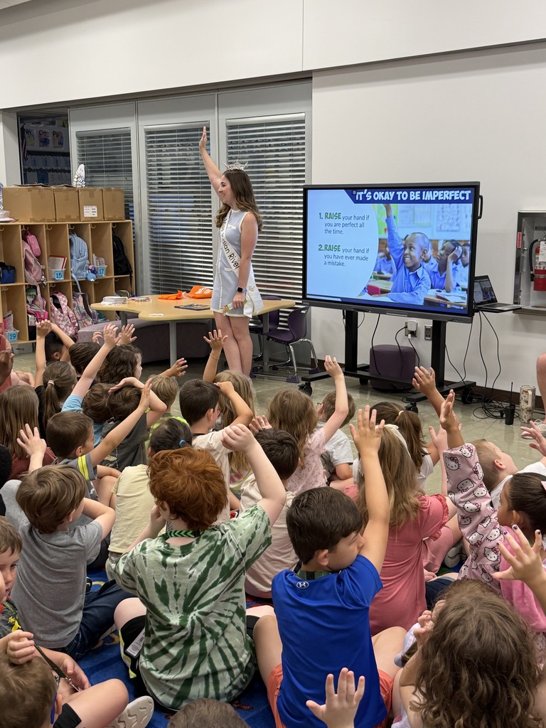 Miss Indian River asks students a question during her lesson as children eagerly raise their hands to participate.