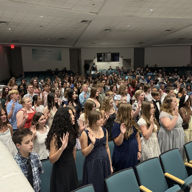 students standing in the auditorium reciting the pledge 