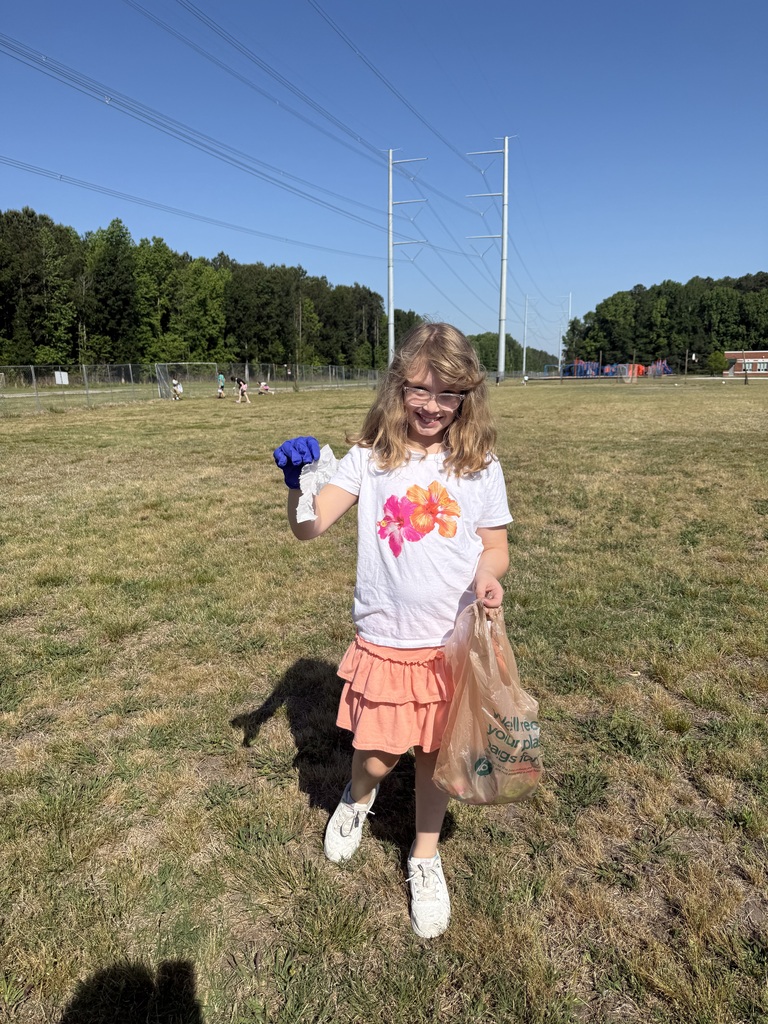 One of Mrs. Charlton's students holding a brown plastic bag that she is putting trash into.