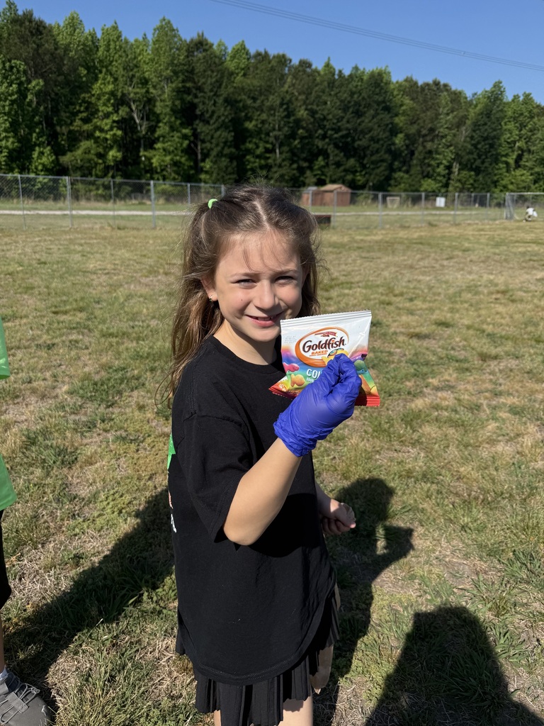 One of Mrs. Charlton's students holding up a bag of Goldfish snacks bag that was left as trash on the ground.