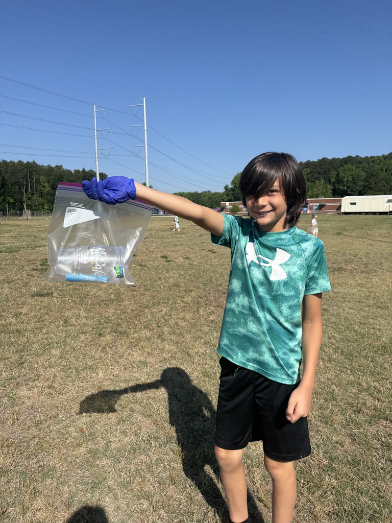 One of Mrs. Charlton's students holding up a zip lock back with trash in it.