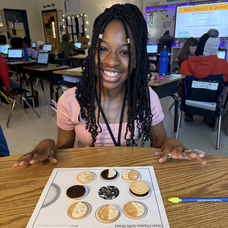 Close-up of elementary students using Oreo cookies to review moon phases for the Science SOL. The cookies are scraped to show different amounts of cream, representing the phases arranged on a paper.