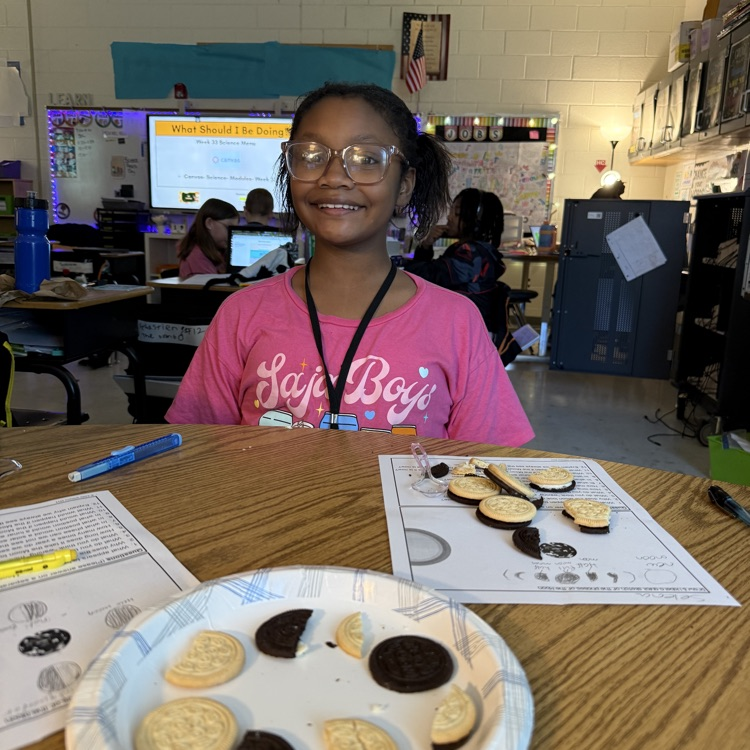 Close-up of elementary students using Oreo cookies to review moon phases for the Science SOL. The cookies are scraped to show different amounts of cream, representing the phases arranged on a paper.