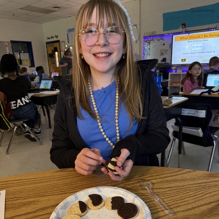 Close-up of elementary students using Oreo cookies to review moon phases for the Science SOL. The cookies are scraped to show different amounts of cream, representing the phases arranged on a paper.