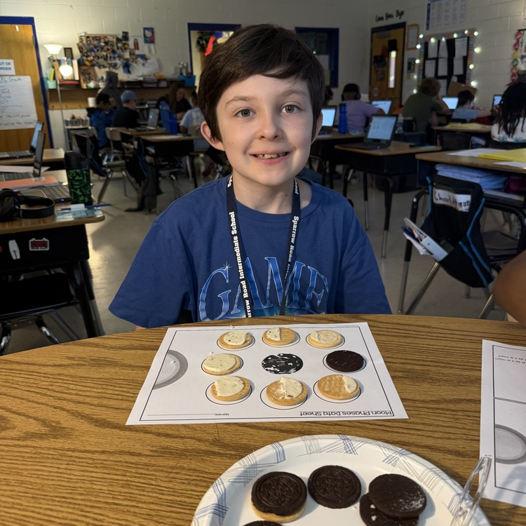 Close-up of elementary students using Oreo cookies to review moon phases for the Science SOL. The cookies are scraped to show different amounts of cream, representing the phases arranged on a paper.