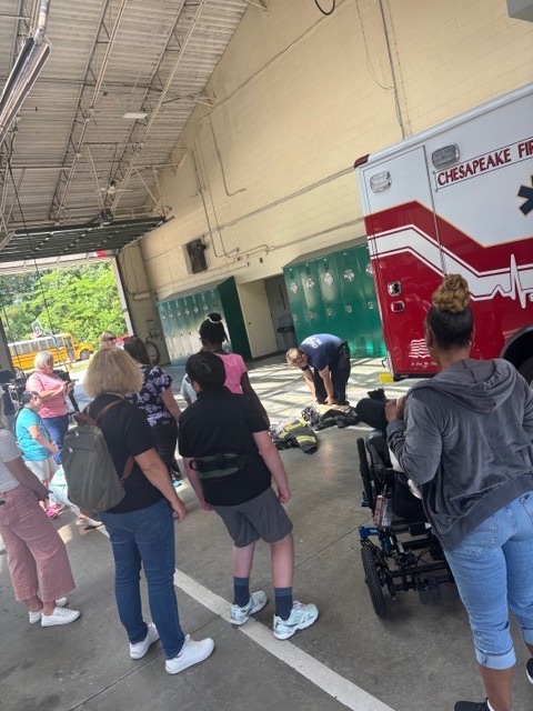 students watching while firefighter shows all the pieces of their uniform