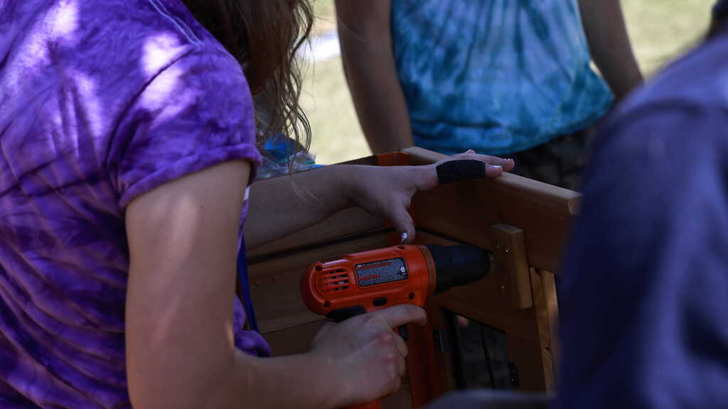 A DCH student uses a drill to screw in a screw