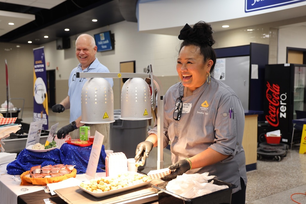 Food vendors smiling and serving samples.