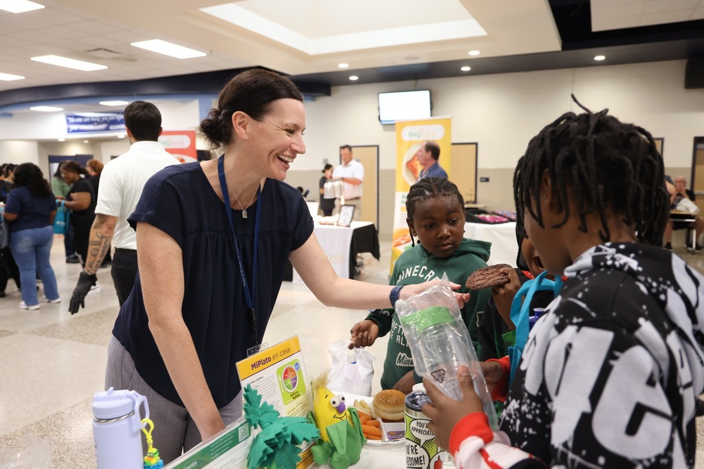 A food vendor interacting with students and showing them sample items.