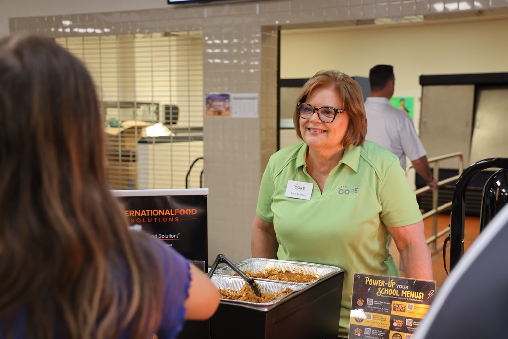 Food vendors smiling and serving samples.