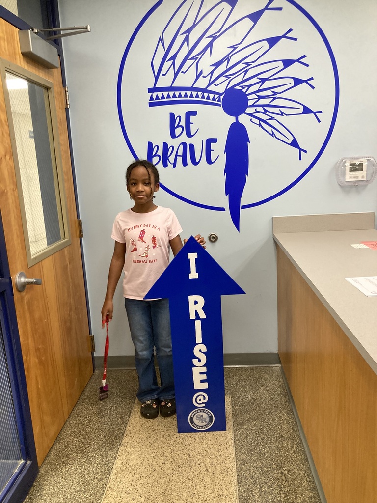 Student RISE award winner smiling and holding the RISE arrow.