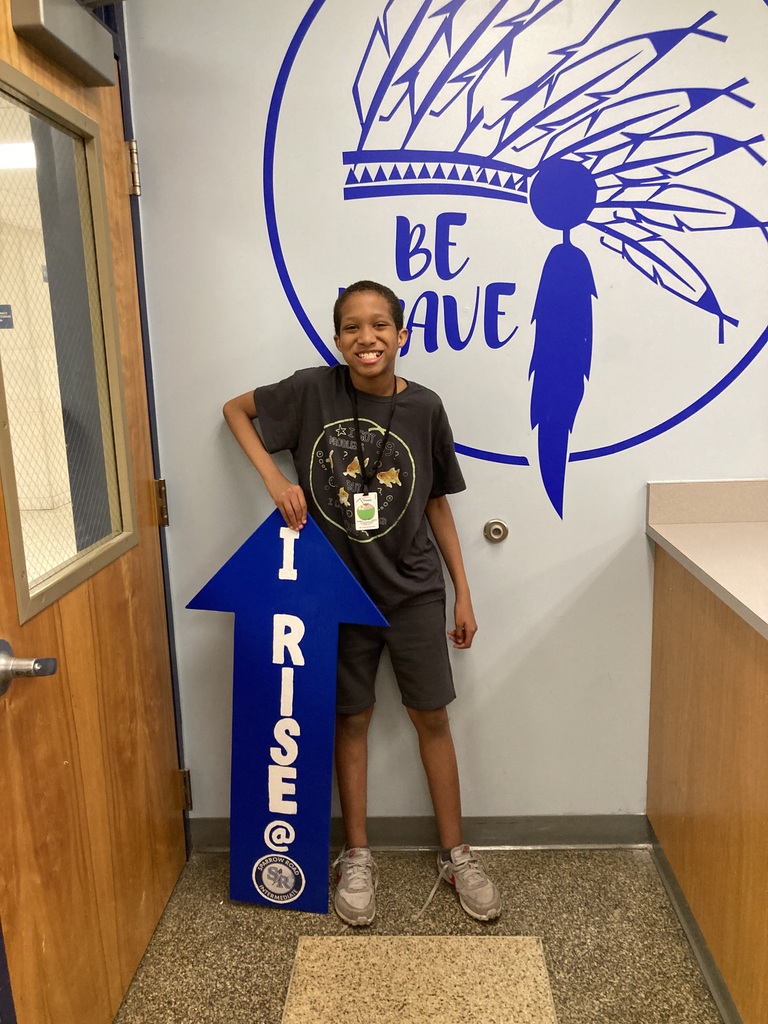 Student RISE award winner smiling and holding the RISE arrow.