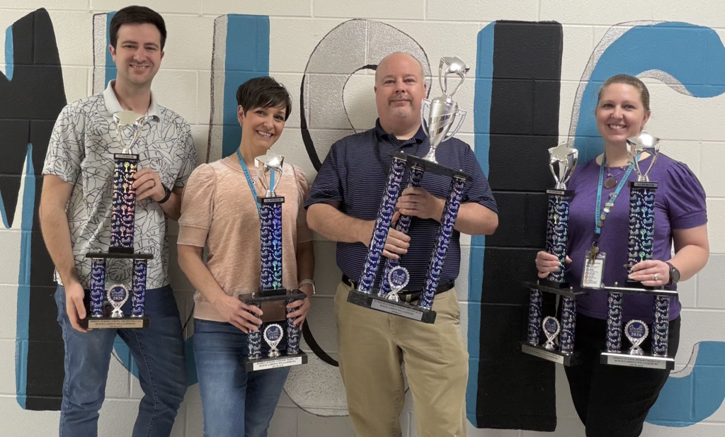 Music teachers standing proudly with their first place trophies