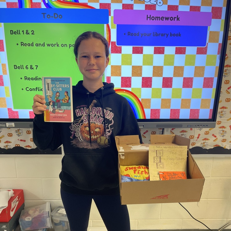 student smiling, holding graphic novel and Work in English class