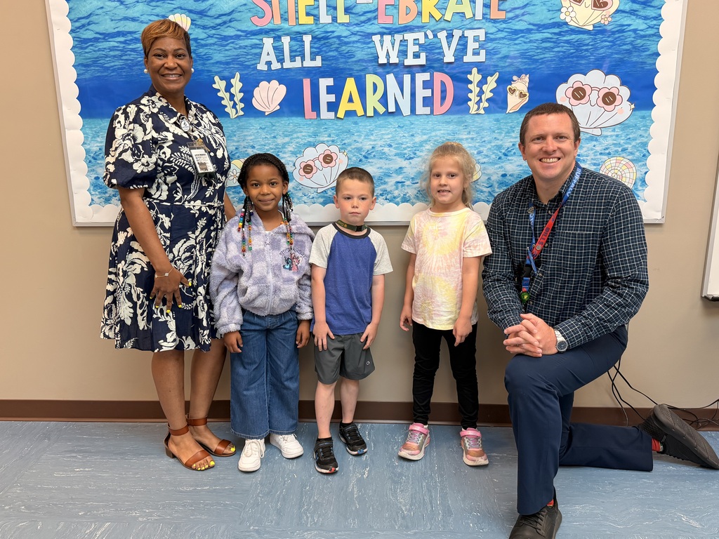 A group of Students of the Month for May posing with the school principal and assistant principal, smiling for the camera in a celebratory recognition photo.