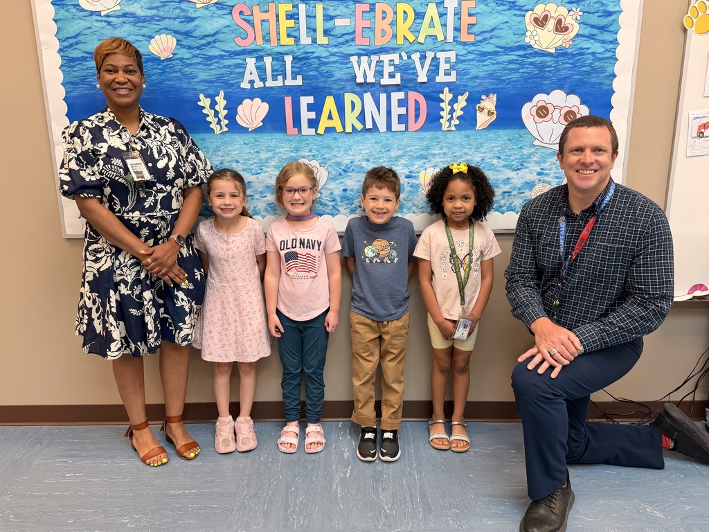 A group of Students of the Month for May posing with the school principal and assistant principal, smiling for the camera in a celebratory recognition photo.