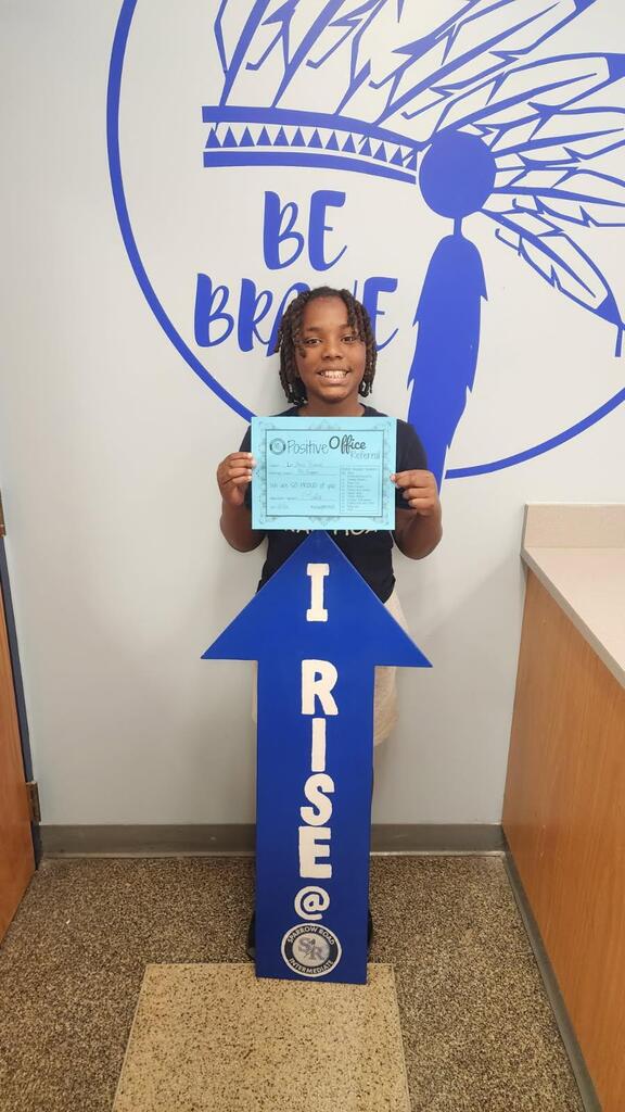 Student proudly holding up Positive Office Referral with the I RISE arrow.