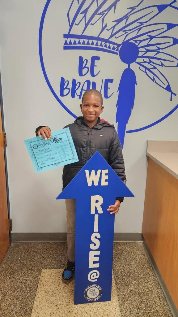 Student proudly holding up Positive Office Referral with the I RISE arrow.