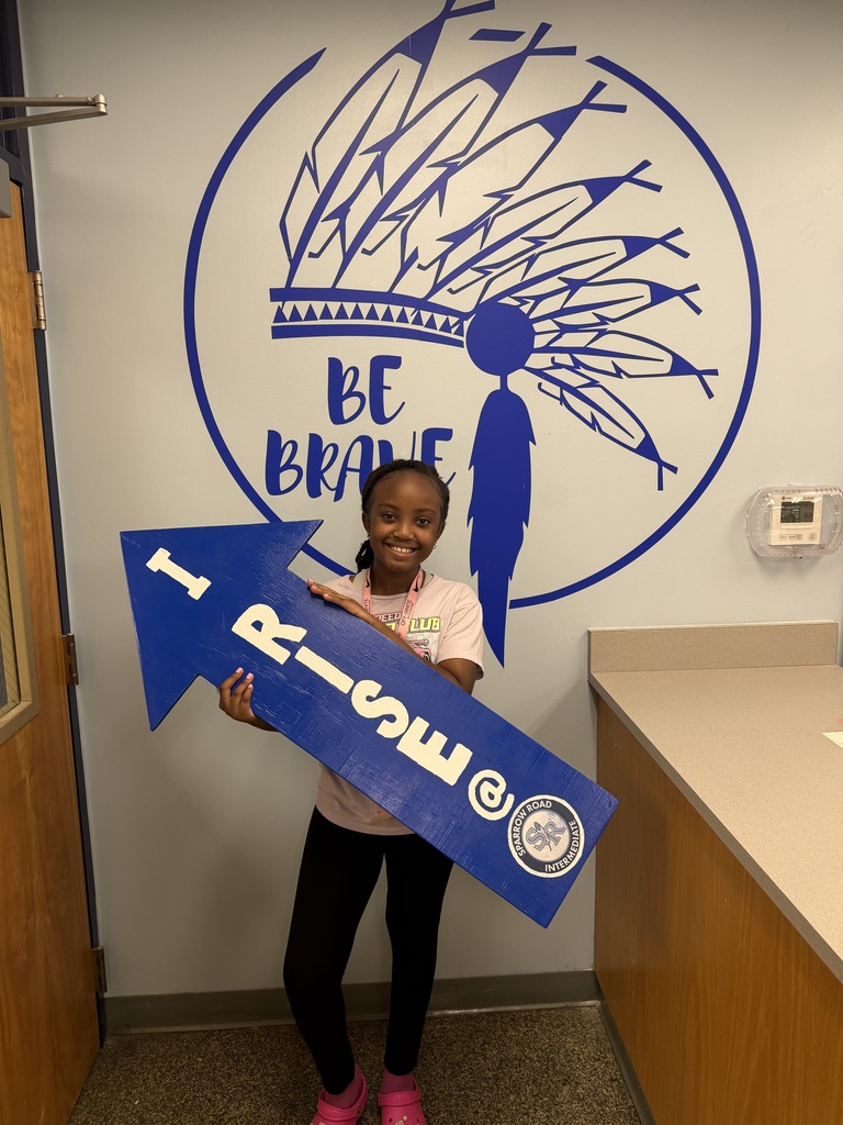 Student proudly holding up the I RISE arrow.