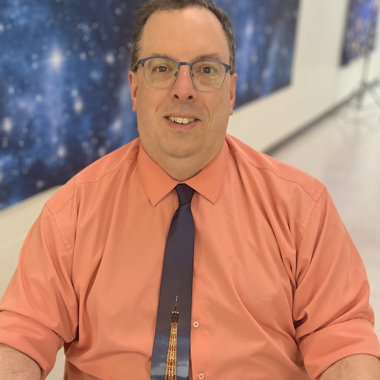 Mr. Drotar smiling in an orange shirt 
