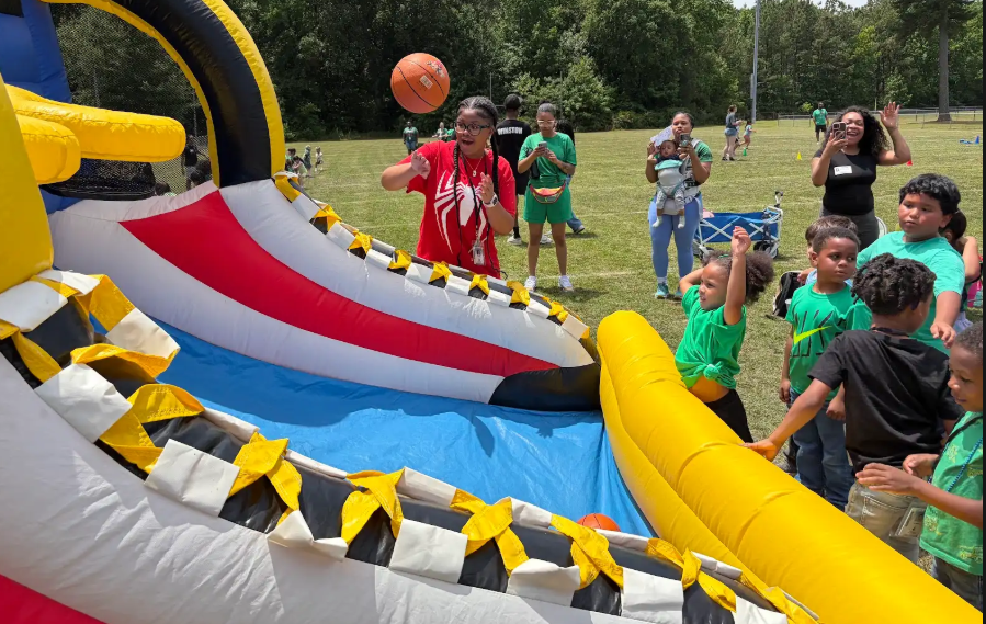 students playing at an inflatable basketball hoop outside