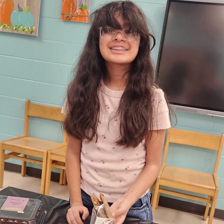 student smiling while preparing for the bake sale