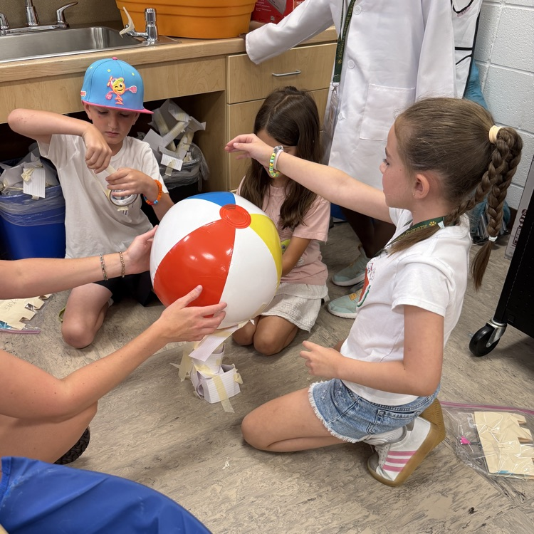 students working together to build a tower of flashcards to hold a beach ball
