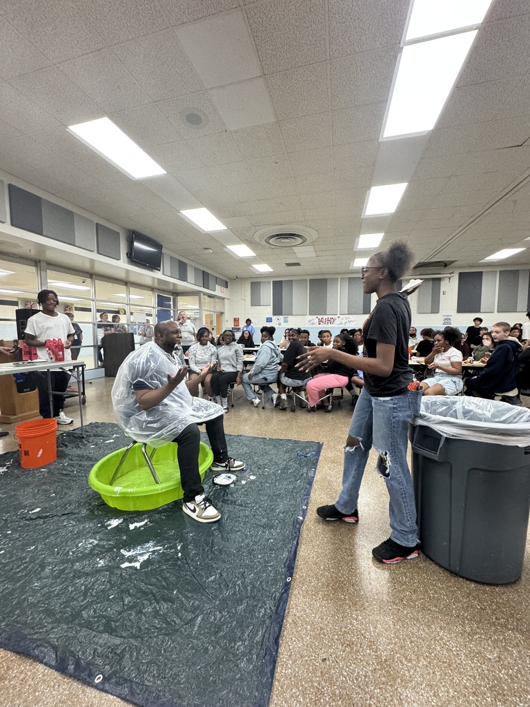 Students throwing a pie at a staff member  during a field Day activity.